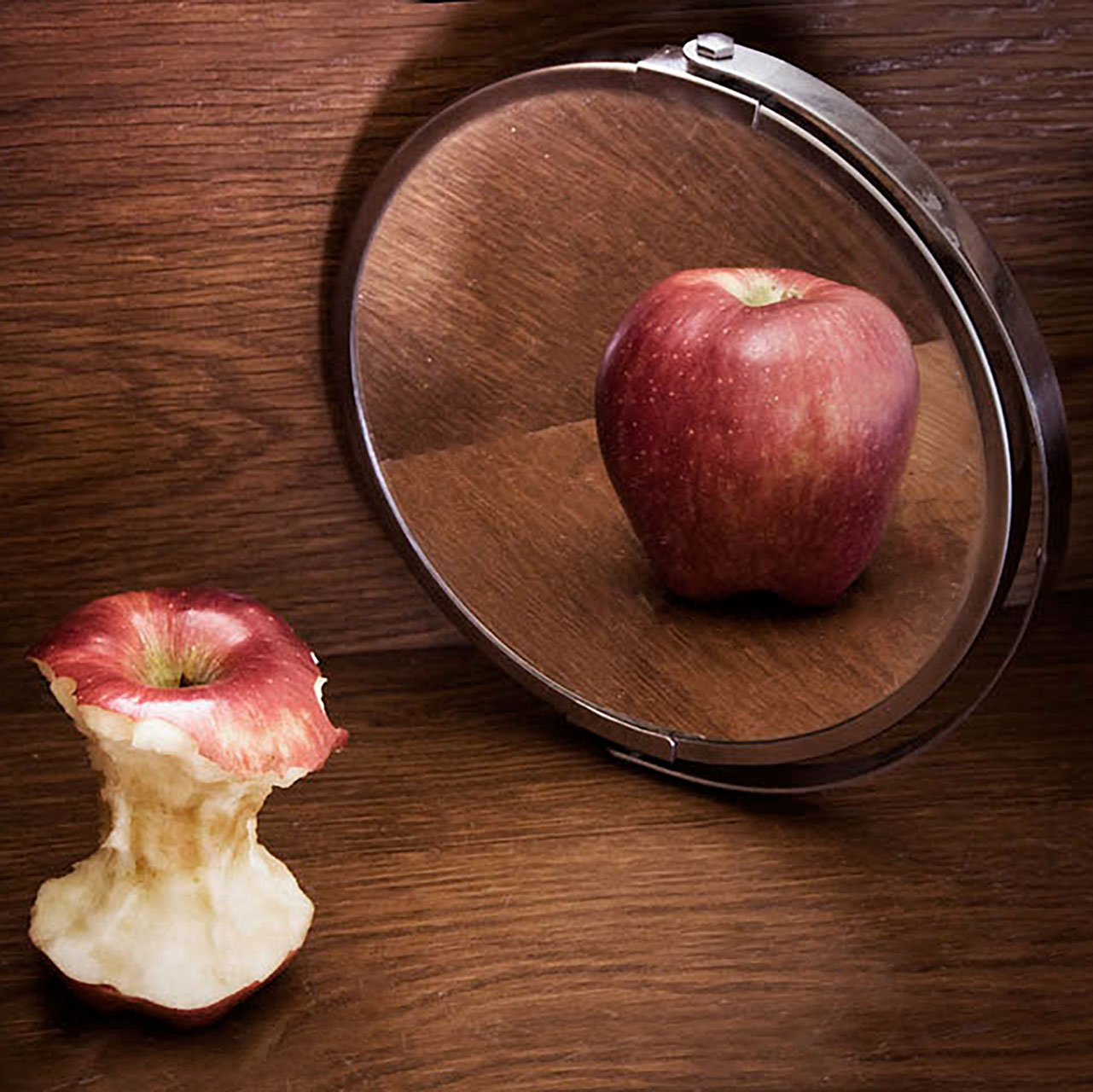Et æbleskrog med en refleksion af et helt æble i et spejl som symbol på spiseforstyrrelse man kan få terapi for hos Psykolog i København psykolog Morten Skyum Nielsen