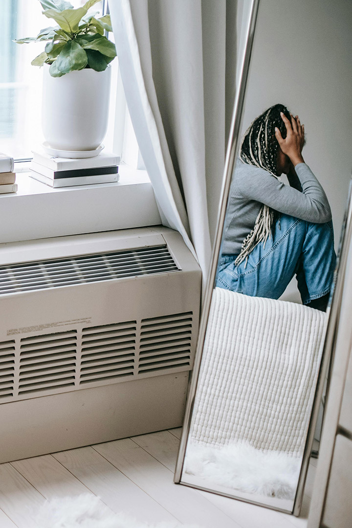 Reflektion af kvinde i et spejl som sidder krøllet sammen og får terapi for udviklingstraumer hos psykolog i København psykolog Morten Skyum Nielsen